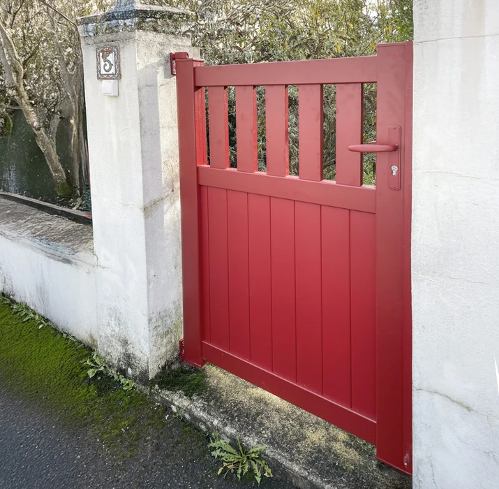Extérieur résidentiel avec portillon d'entrée rouge en bois à lames verticales et claire-voie supérieure