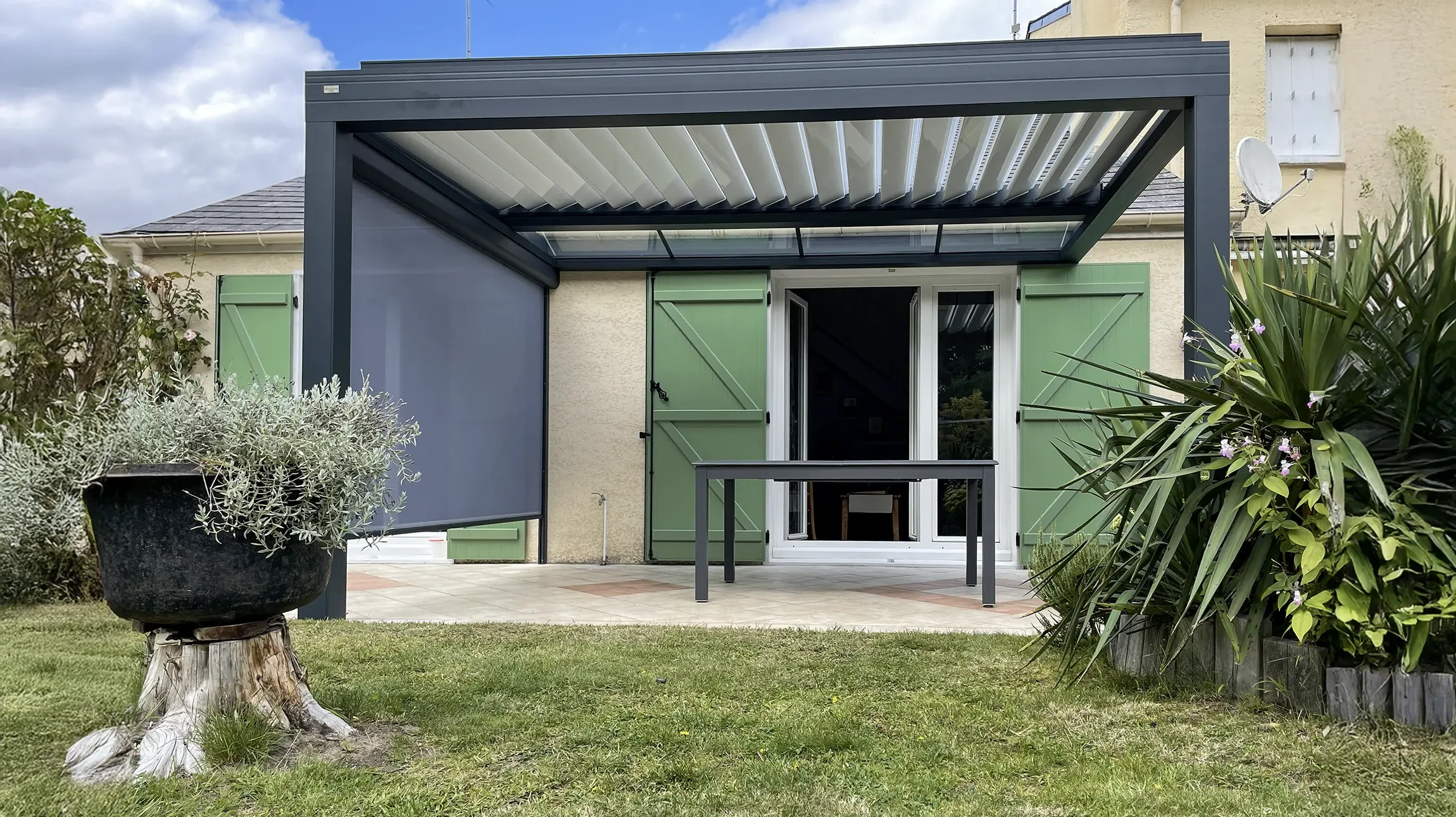 Entr&eacute;e de maison r&eacute;sidentielle avec porte d'entr&eacute;e ouverte donnant sur patio ext&eacute;rieur ensoleill&eacute;