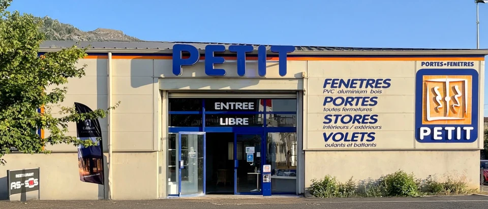 Intérieur d'habitation avec grandes fenêtres à battants ouvertes donnant sur jardin enneigé